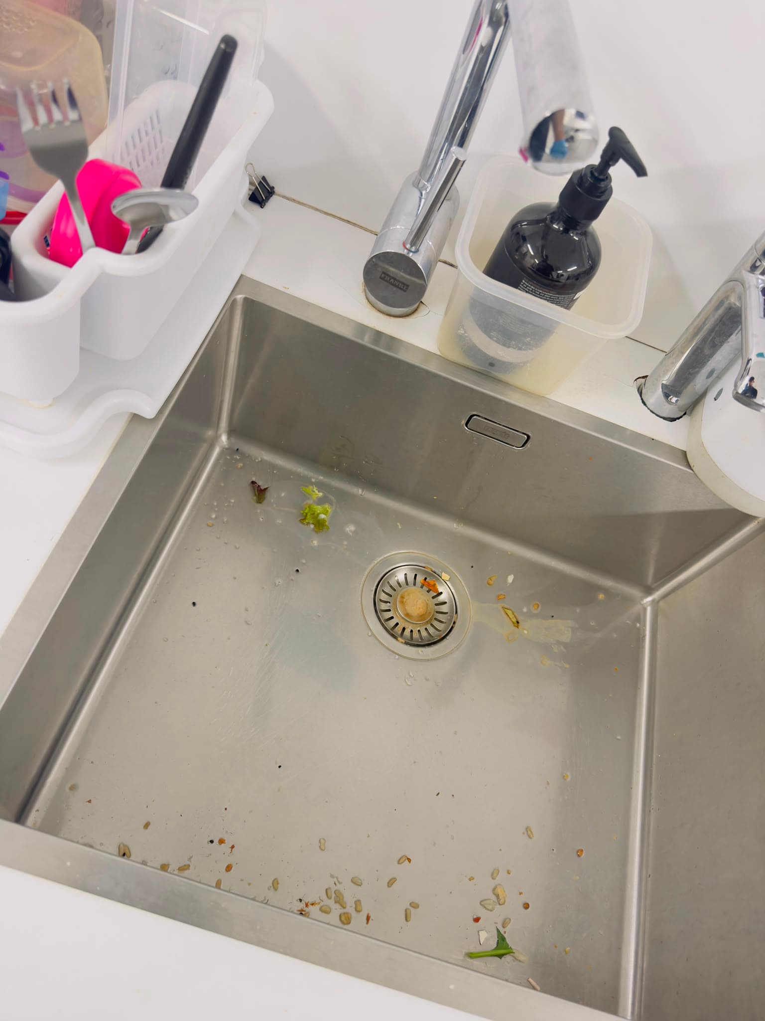 Stainless kitchenette sink with food scraps before cleaning